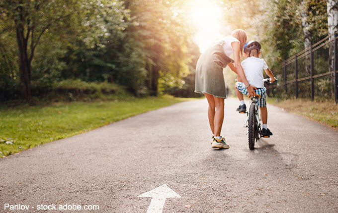 Mutter hilft Kind beim Fahrradfahren