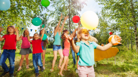 Kinder spielen mit Luftballons im Grünen